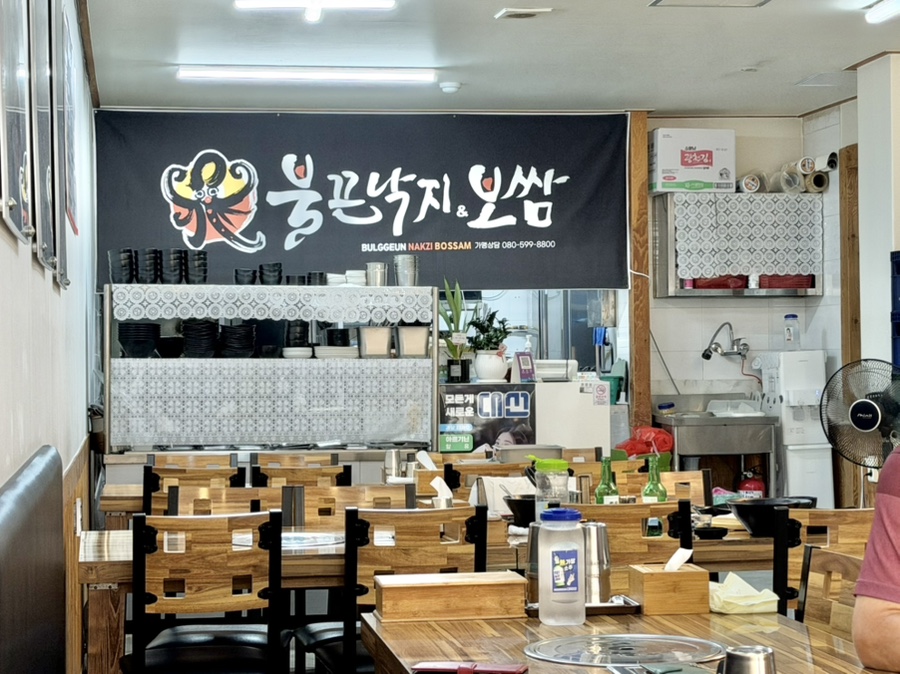 원목 테이블이 놓인 매장 내부와 벽면의 불끈낙지&보쌈 간판