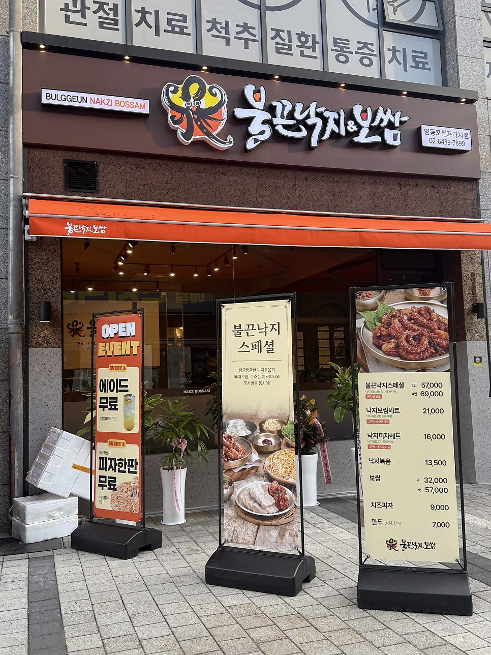 낮에 본 매장 정면 — 문어 캐릭터 간판과 나란히 세워진 이벤트·메뉴 배너