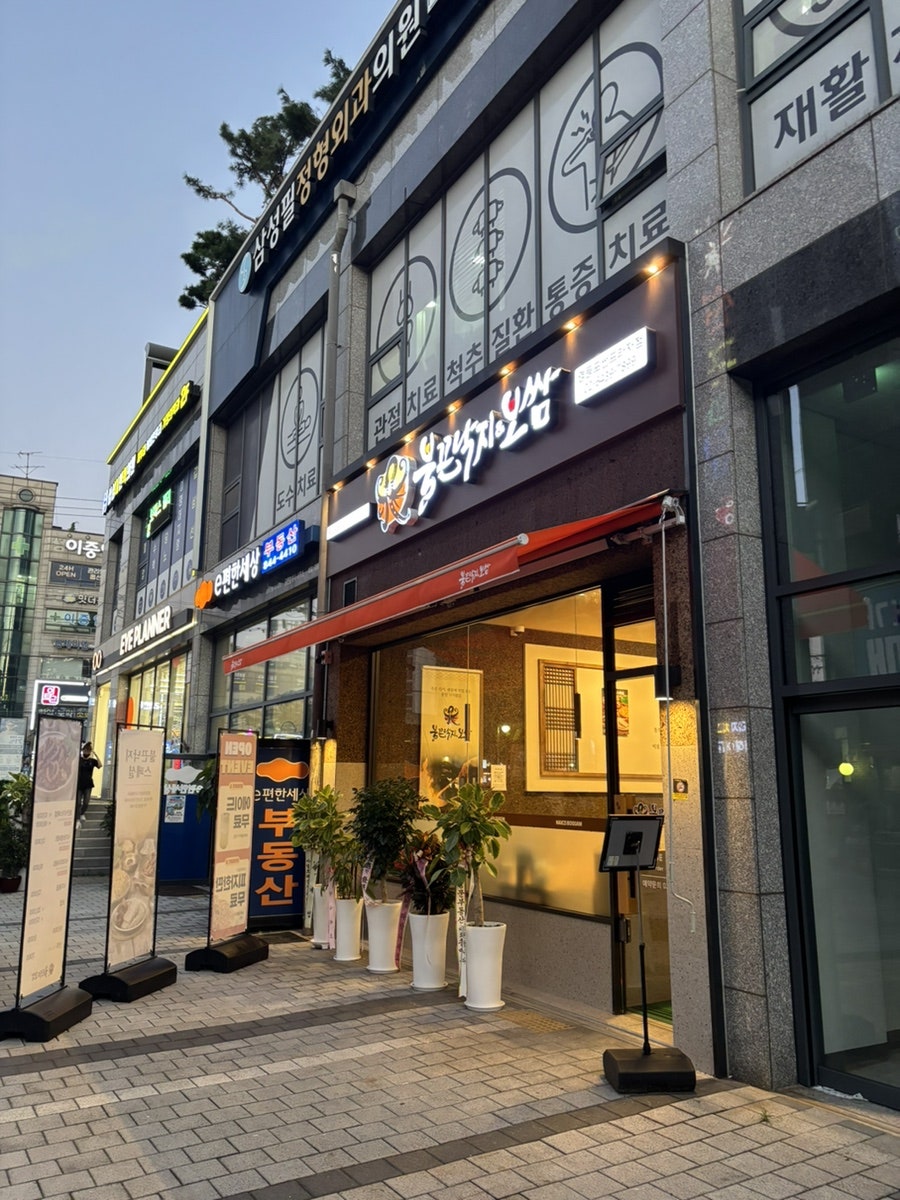 해질 무렵 불을 밝힌 매장 외관, 입구 옆에 메뉴 안내판이 서 있다