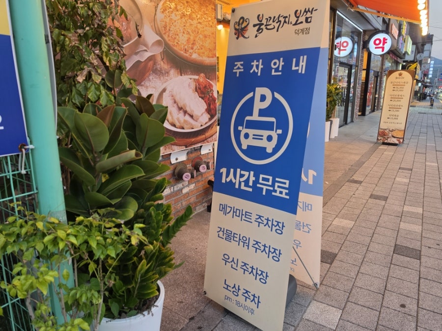 매장 앞 주차 안내 입간판 — 메가마트·건물타워·우신 주차장, 노상주차 1시간 무료