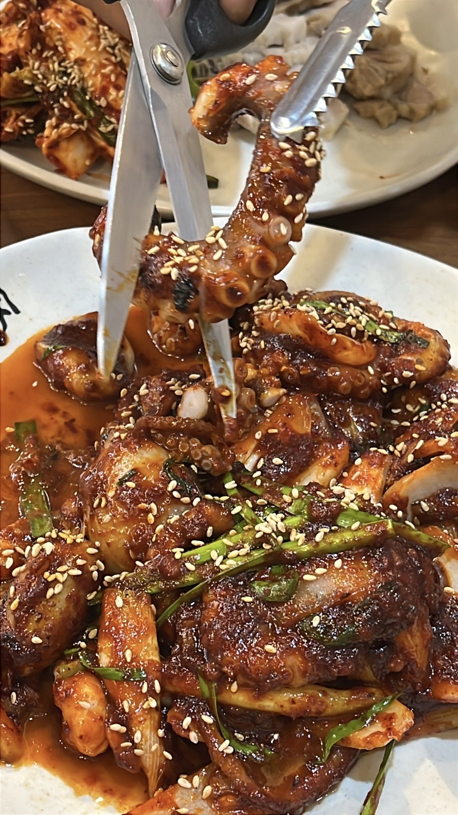 가위로 잘라 나누는 두툼한 낙지 다리. 양념이 고르게 배어 있다