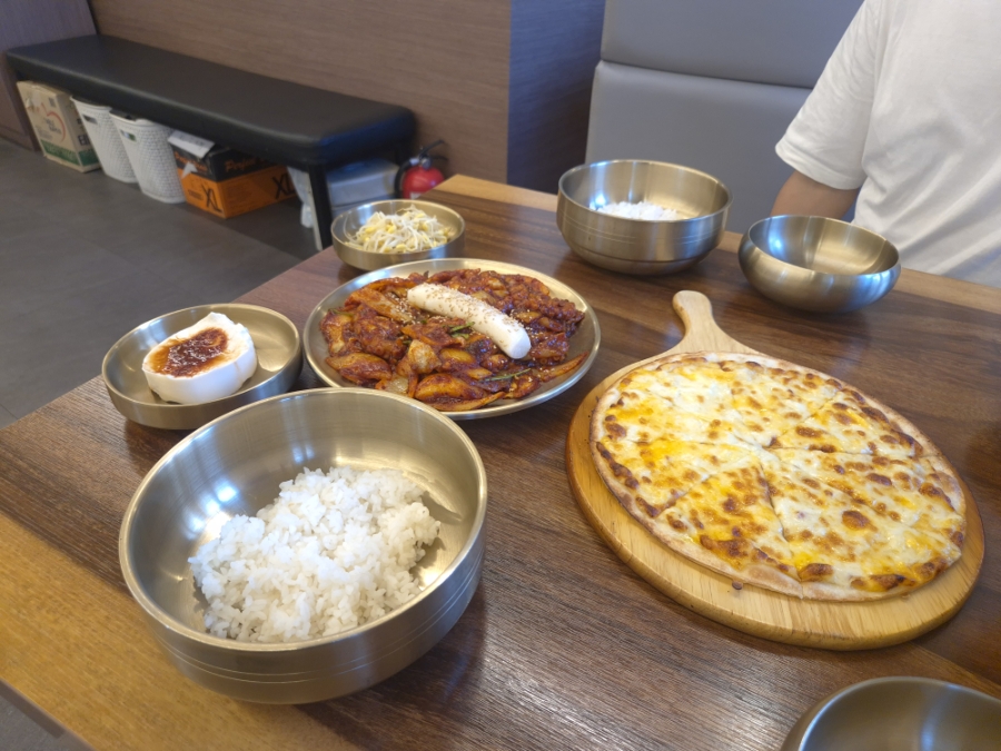 낙지볶음과 고르곤졸라피자, 놋그릇에 담긴 밥과 기본 찬으로 차려진 낙지 피자세트 2인 상차림.
