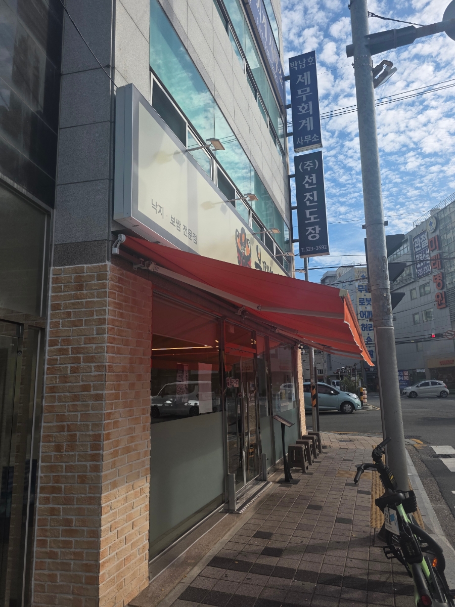 '낙지·보쌈 전문점' 문구가 적힌 측면 간판과 붉은 어닝이 이어진 매장 외부