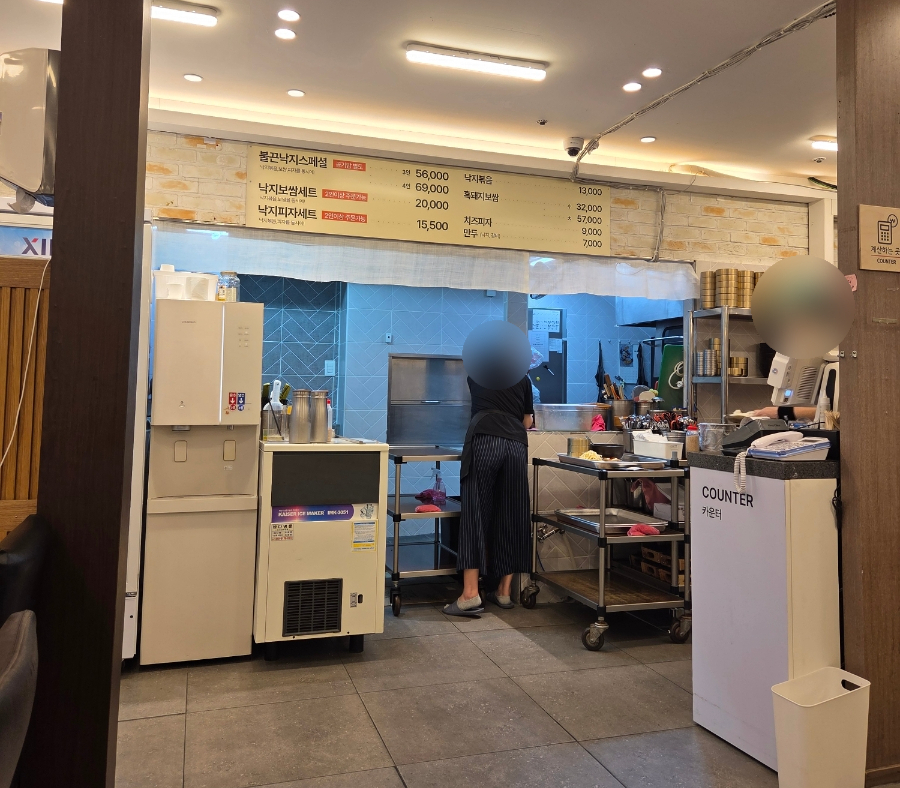 주방이 홀로 열린 오픈키친과 대표 메뉴 가격이 적힌 보드, 셀프 정수기 코너