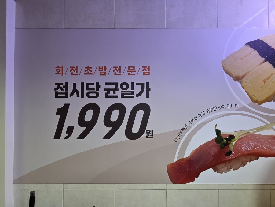 벽면에 붙은 '접시당 균일가 1,990원' 안내. 계란초밥과 참치초밥 이미지가 함께 들어가 있다.