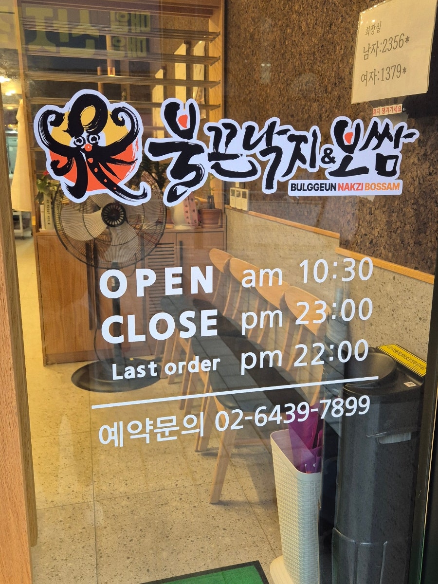 유리문 안쪽으로 보이는 목재 테이블과 영업시간 안내