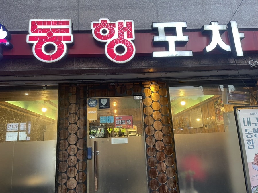 나무 마감과 조명이 보이는 동행포차 구포본점 출입구 근접 모습