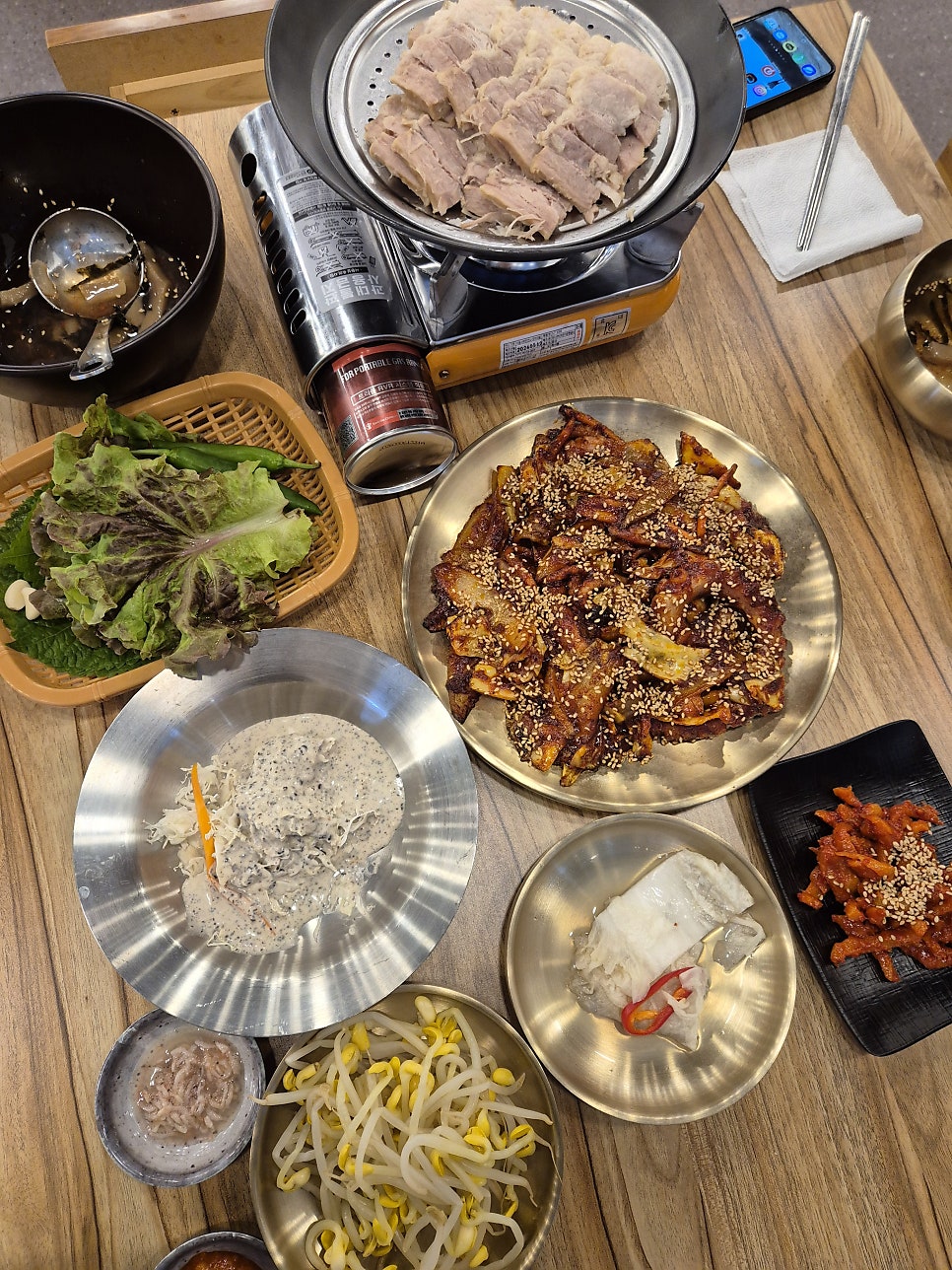 버너 위 찜기에 올려 나온 보쌈과 낙지볶음, 흑임자 샐러드와 콩나물 등 기본 반찬.