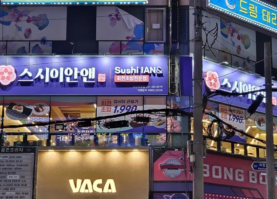 저녁 시간 불을 밝힌 간판. '회전초밥 접시당 균일가 1,990원' 문구가 선명합니다.