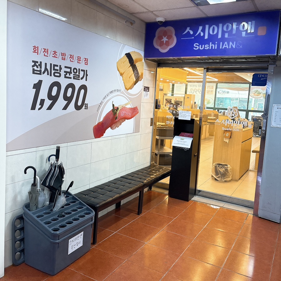 매장 입구와 복도 쪽 대기 의자. 우산꽂이와 균일가 안내 포스터가 함께 놓여 있습니다.