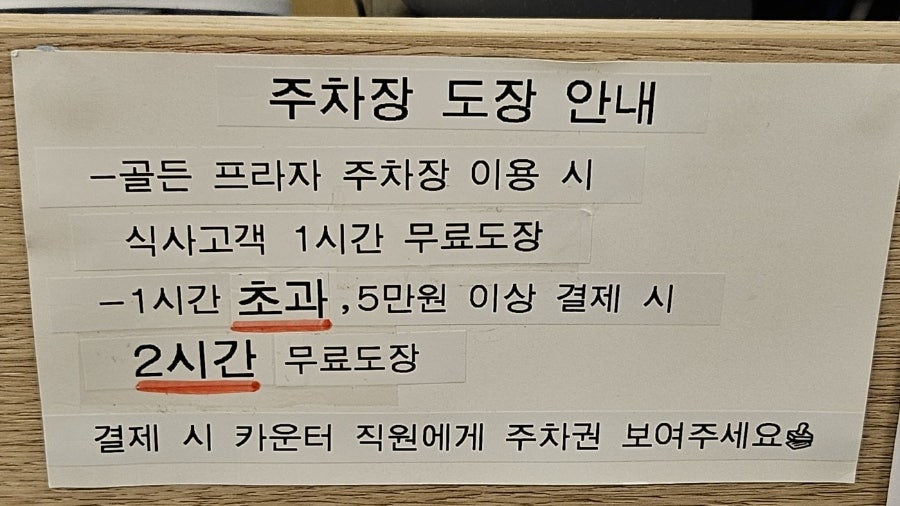 카운터에 붙은 주차장 도장 안내. 식사 고객 1시간, 5만 원 이상 결제 시 2시간 무료입니다.