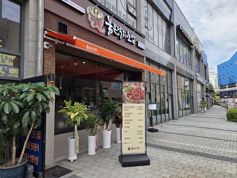 입구 옆 스탠드 메뉴판. 불끈낙지스페셜, 낙지보쌈세트, 낙지피자세트, 보쌈, 치즈피자 가격이 적혀 있습니다.