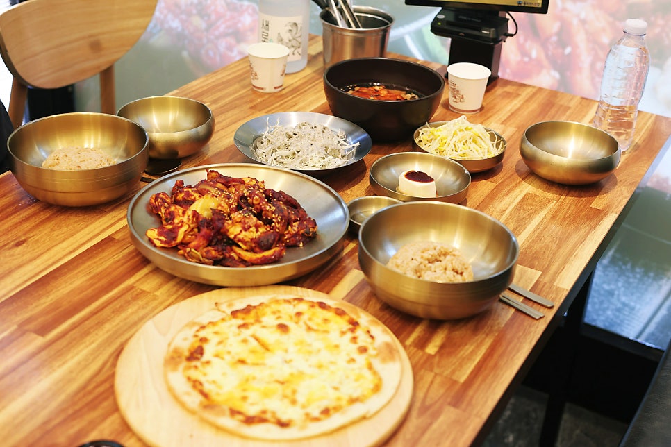 유기 그릇에 담겨 나온 낙지볶음과 흑마늘밥, 묵사발, 고르곤졸라 피자 한 상.