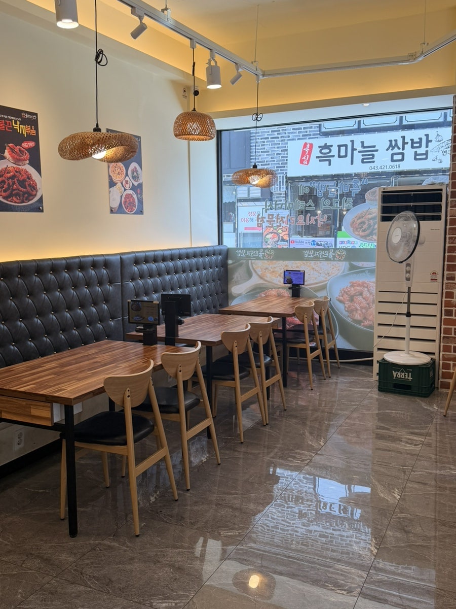 소파석과 원목 테이블이 놓인 매장 내부. 테이블마다 주문 태블릿이 있습니다.